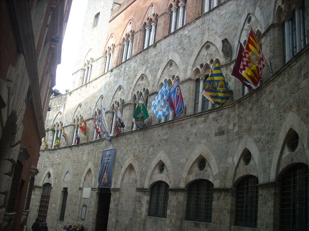 Le bandiere delle contrade sventolano nei palazzi di Siena